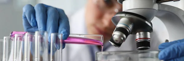 Asistente de laboratorio vierte líquido para su examen — Foto de Stock