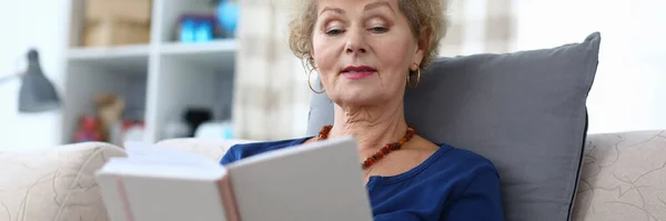 Grandmother sits at home and reads with enthusiasm — Stock Photo, Image