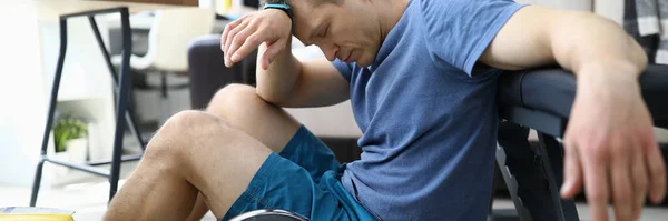 Cansado de esportes exercícios cara senta-se no chão em casa — Fotografia de Stock