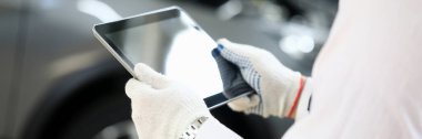 Adam sorun çıkarmak için arabanın yanında tablet tutuyor.