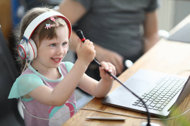 Çocuk kulaklıkla sandalyeye oturur ve mikrofonu elleriyle tutar..