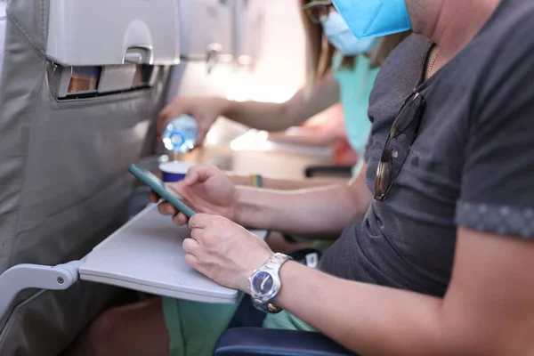 El hombre sostiene el teléfono en sus manos mientras está sentado silla en el avión — Foto de Stock