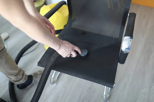 Adam elektrikli süpürgeyle sandalyeden toz temizliyor.. — Stok fotoğraf