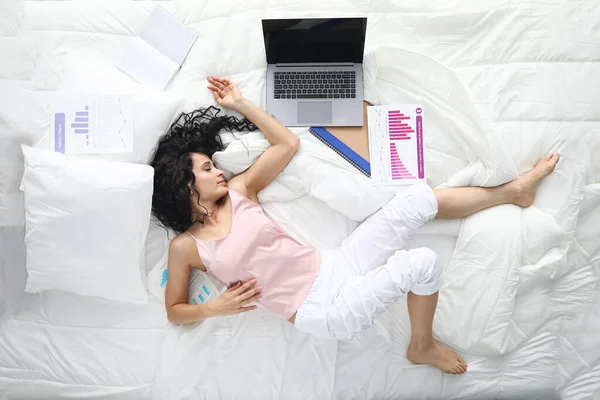 Втомилася жінка в піжамі спить в позі в білому ліжку . — стокове фото
