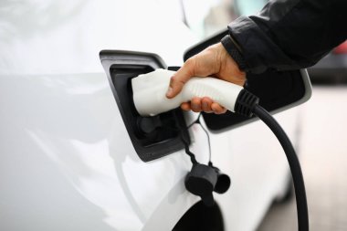 Şarj istasyonunda beyaz elektrikli araba şarj edilecek..