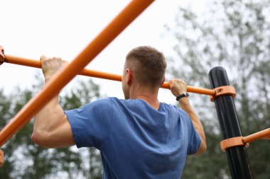 Mavi tişörtlü adam kendini parktaki yatay bara çekti..
