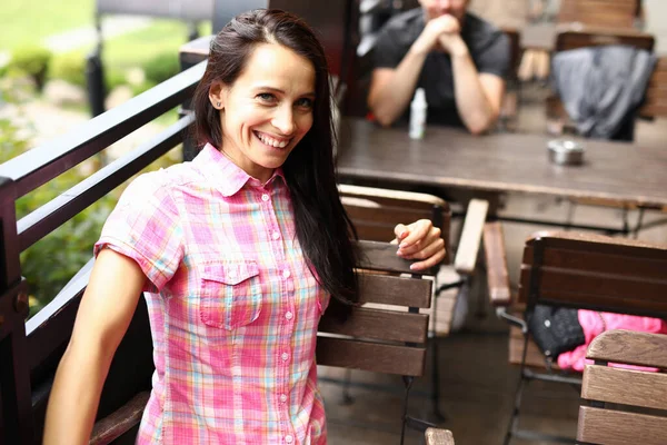 Mutlu kadın yaz kafesinde kahverengi sandalyeye oturur..