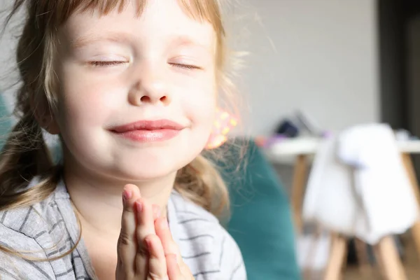 Bambina con gli occhi chiusi sorride e tiene insieme le penne. — Foto Stock