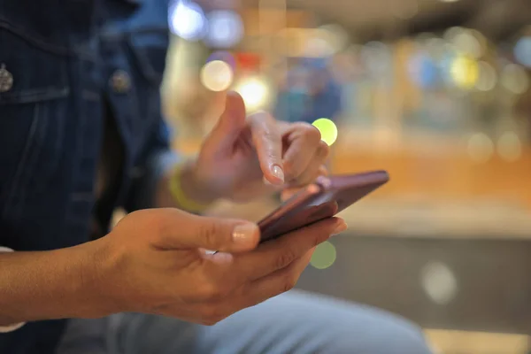 Mão das mulheres segura smartphone e move o dedo através da tela. — Fotografia de Stock