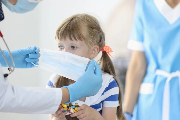 Kleines Mädchen setzt beim Arzttermin medizinische Schutzmaske auf — Stockfoto