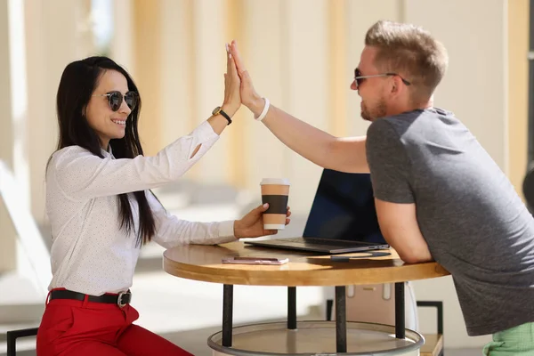 Smiling man and woman greet high five agreement.