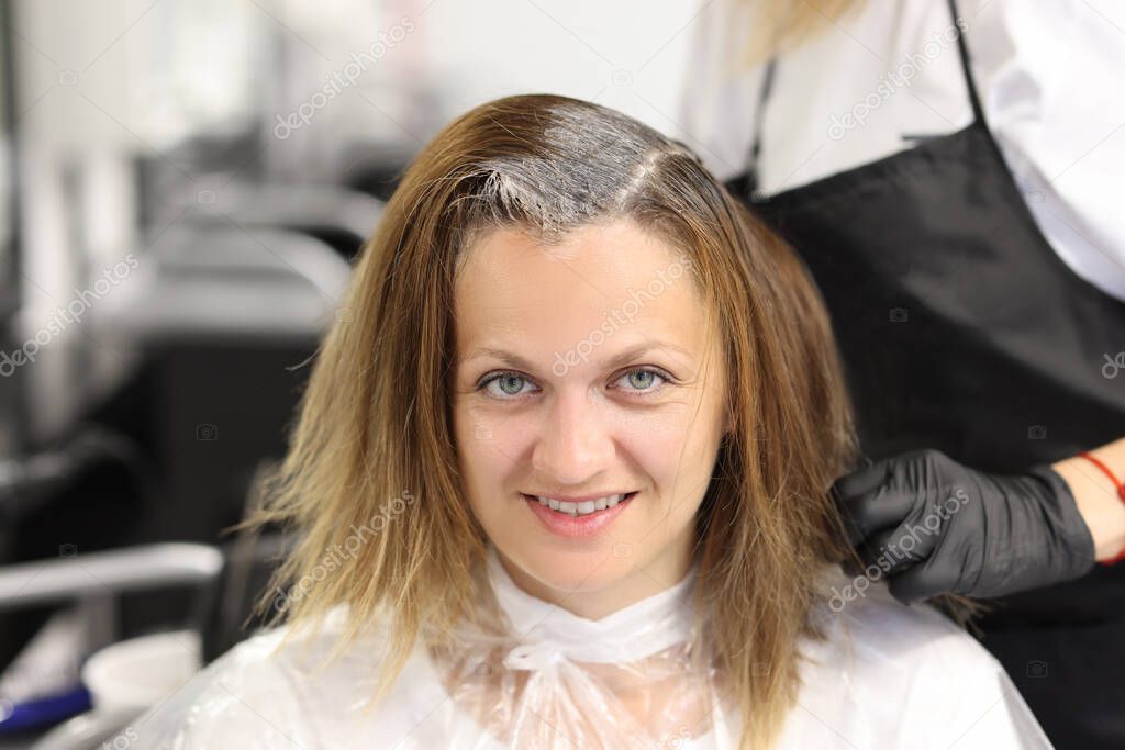 Woman in hairdressing salon paints hair roots