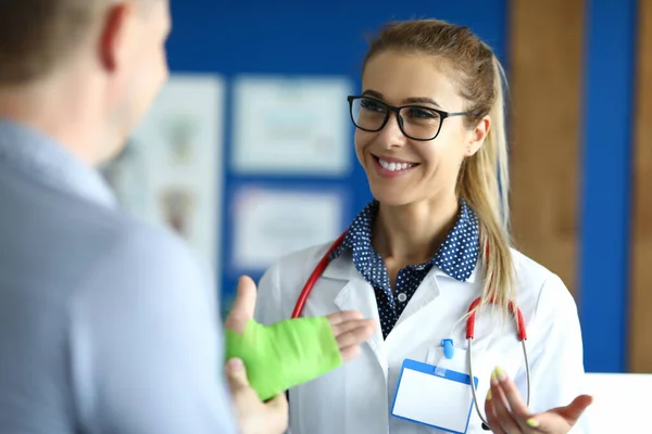 Medico sta con paziente il cui braccio è fasciato. — Foto Stock