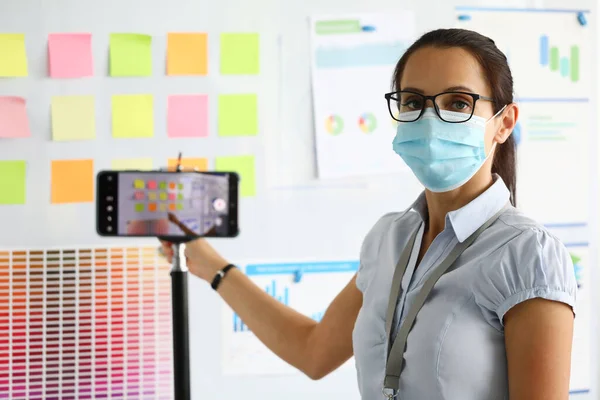 Mulher em máscara médica protetora realiza conferência de negócios e registra-o no smartphone. — Fotografia de Stock