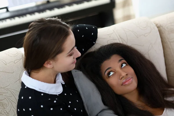 Girlfriends are sitting on couch smiling and chatting. — Stock Photo, Image