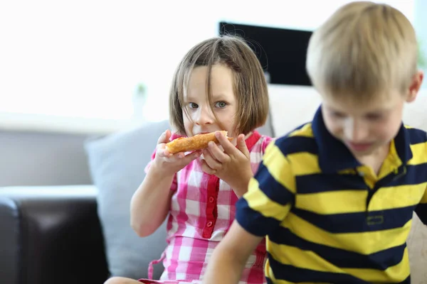 Pequeña niña come pizza un niño está de pie junto a ella. —  Fotos de Stock