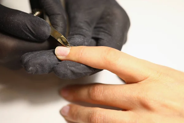 Manicura con guantes utiliza pinzas para cortar cutículas en las uñas. — Foto de Stock