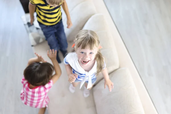 Ragazzo e ragazze ridono e saltano sul divano a casa. — Foto Stock