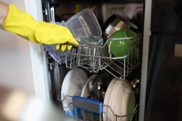 A tiszta edényeket kiveszik a nyitott mosogatógépből sárga kesztyűben.. — Stock Fotó
