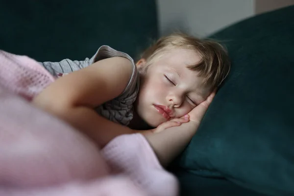 Little girl sleeps in bed with her arms folded under her head. — Stock Photo, Image