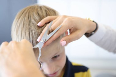 Usta kuaför sarışın çocuğun kâküllerini kesiyor..