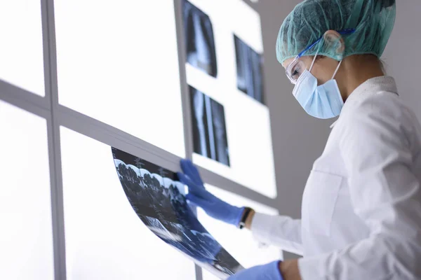 Docteur en masque médical de protection et gants examine une radiographie. — Photo