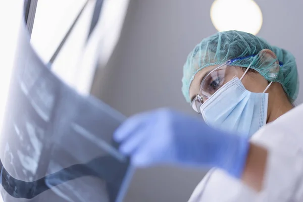 Dokter in beschermende medische masker kijkt naar een röntgenfoto. — Stockfoto