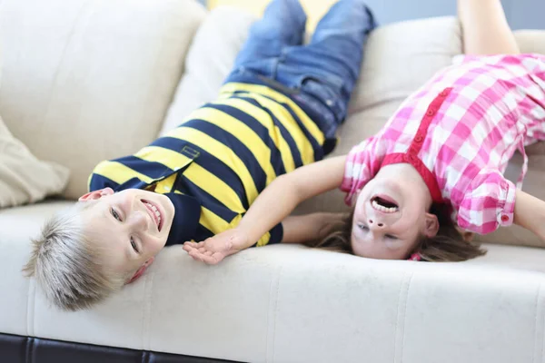 Ragazzo e una ragazza si trovano a testa in giù sul divano e ridono. — Foto Stock
