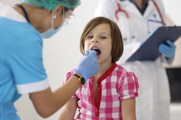 Doctor examines throat of little girl closeup — Stock Photo, Image