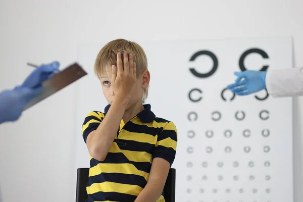 Chlapec u oftalmologa na schůzku zavře jedno oko a odpoví na otázky. — Stock fotografie