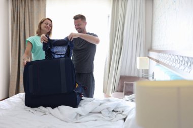 Genç adam ve kadın eşyaları bavula koyuyorlar.