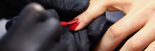 Женщина в черных защитных перчатках делает маникюр крупным планом — стоковое фото