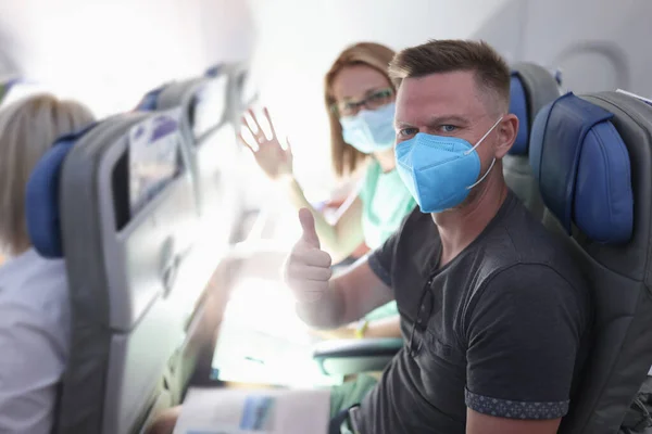 Familia con máscara protectora sentarse en el avión y mostrar sus pulgares hacia arriba. — Foto de Stock