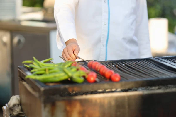 Szakács fehér kabátban grill zöldségek a nyári konyhában. — Stock Fotó