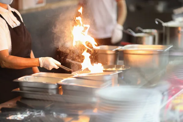 Cook prepare food on fire. Hot flame in pan.