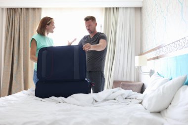 Kolsuz tişörtlü ve şortlu bir kadın odadaki adama bağırıyor..