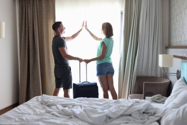 Erkek ve kadın valizin sapını ellerinde tutuyorlar ve birbirlerine beş tane veriyorlar..