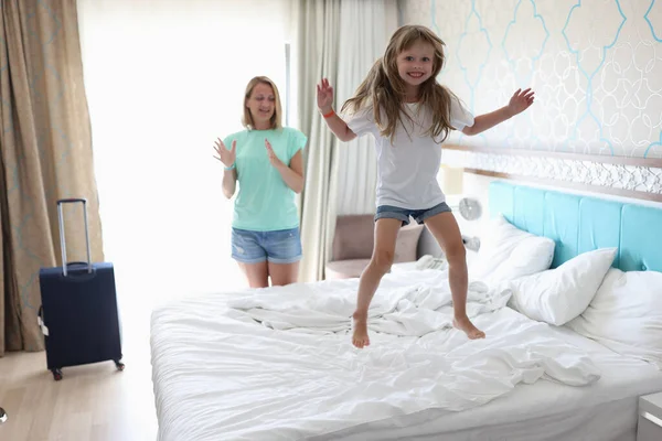 Cheerful girl jump high on bed.