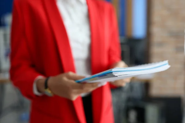 Женщина в красной куртке держит документы в руках крупным планом. — стоковое фото