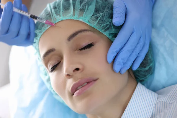 Доктор косметолог вводит инъекции в лоб молодой женщины в салоне красоты — стоковое фото