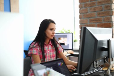Ofisteki kadın bilgisayarın başında oturup monitöre bakıyor..