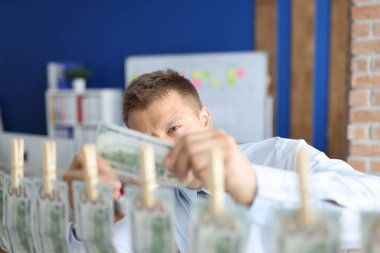 Adam elinde 100 dolar tutuyor. Paraların geri kalanı mandallara asılı..