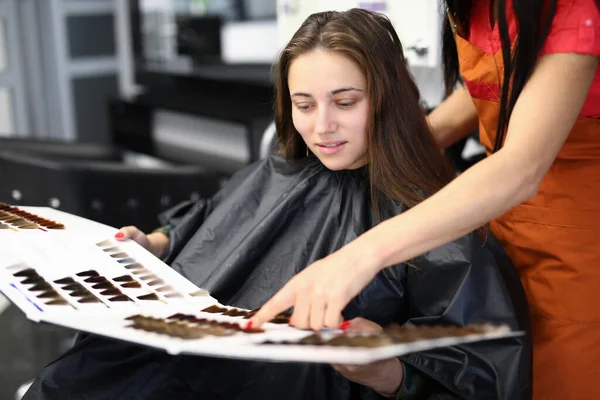 Žena klient s mistrem v salonu krásy zkoumá vzorky palety barev na vlasy — Stock fotografie