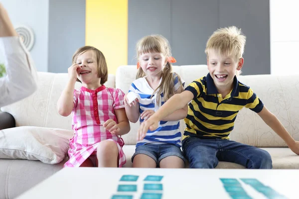 男の子と二人の女の子は笑いとボードゲームをプレイ — ストック写真