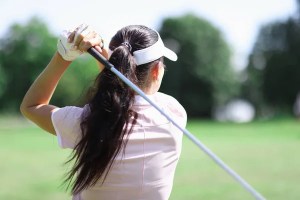Golfista feminina fica de costas e segura o taco de golfe nas mãos. — Fotografia de Stock