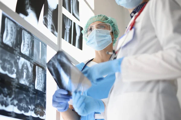 Dos médicos con máscaras protectoras mirando rayos X —  Fotos de Stock