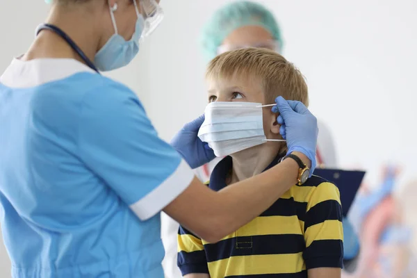 Pojken sätts på skyddande medicinsk mask i läkare kontor. — Stockfoto