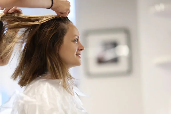 Cliente senta-se na cadeira no cabeleireiro penteando seu cabelo molhado. — Fotografia de Stock