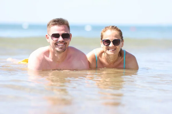 Uomo e donna in occhiali da sole si trovano in mare vicino alla riva. — Foto Stock