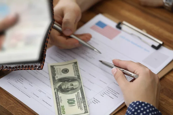 Man holds passport and pen in his hand for filling out visa at foreign embassy closeup